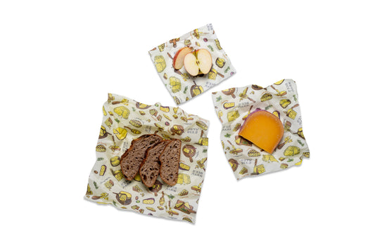 Three reusable wraps with Wheels n Wedges themed pattern, shown on a white background with food props: bread, apple slices, and cheese.
